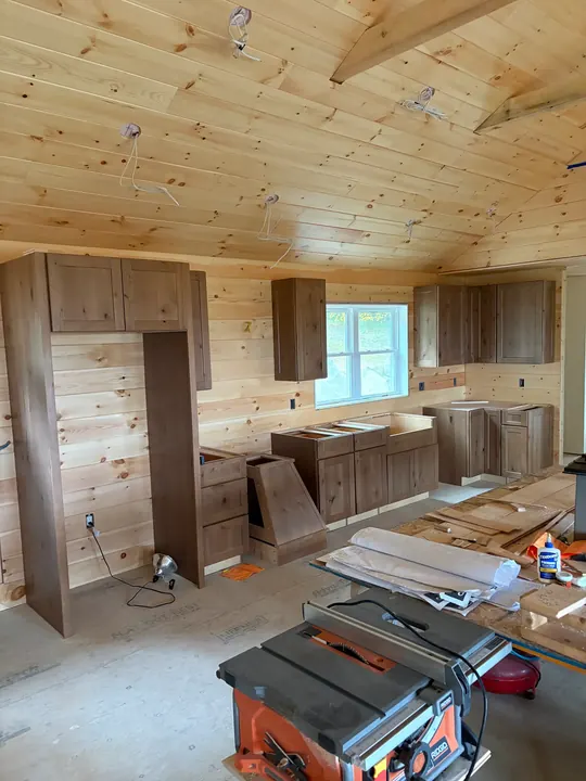 Base, upper and tall pantry cabinets installed in the same pine-paneled room