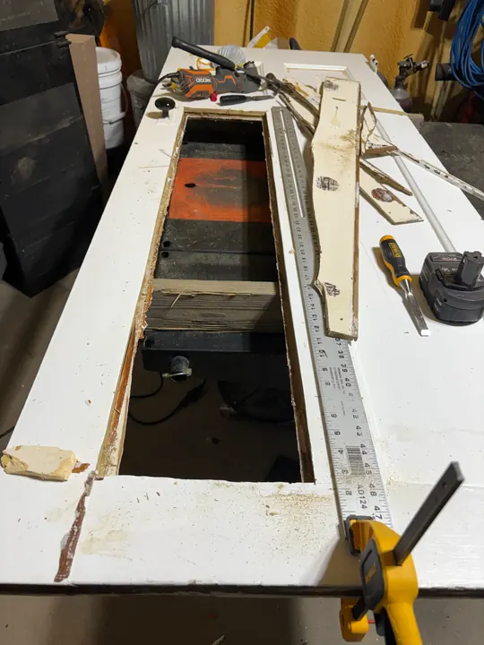 Old painted door on a workbench with a damaged panel cut out