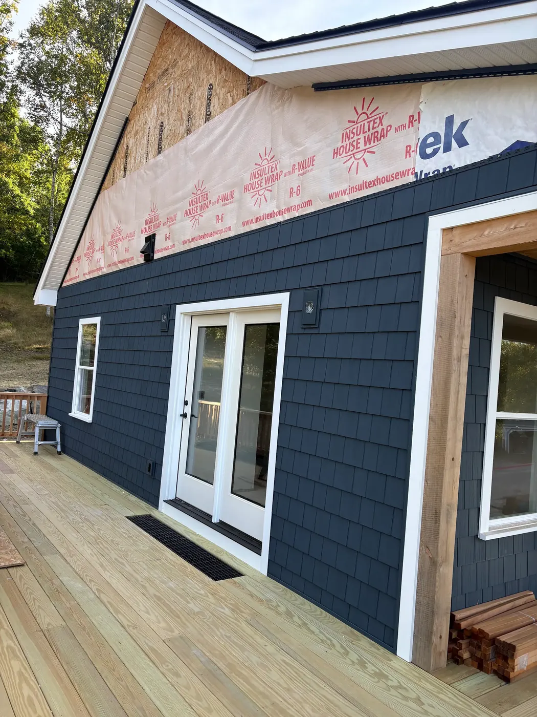 Dark shingle-style siding with white trim around French doors