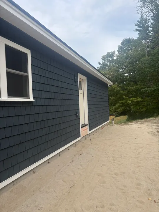Long side wall of a house finished in dark shingle-style siding
